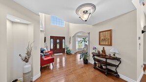A spacious foyer with hardwood flooring, a red sofa, a console table with decorative items, and a large painting on the wall. - Milford Quiet Coastal Retreat 3br Sleeps 8 3 Bedroom Home (Milford)