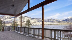 Una terraza de madera con vistas a montañas nevadas y un lago.
