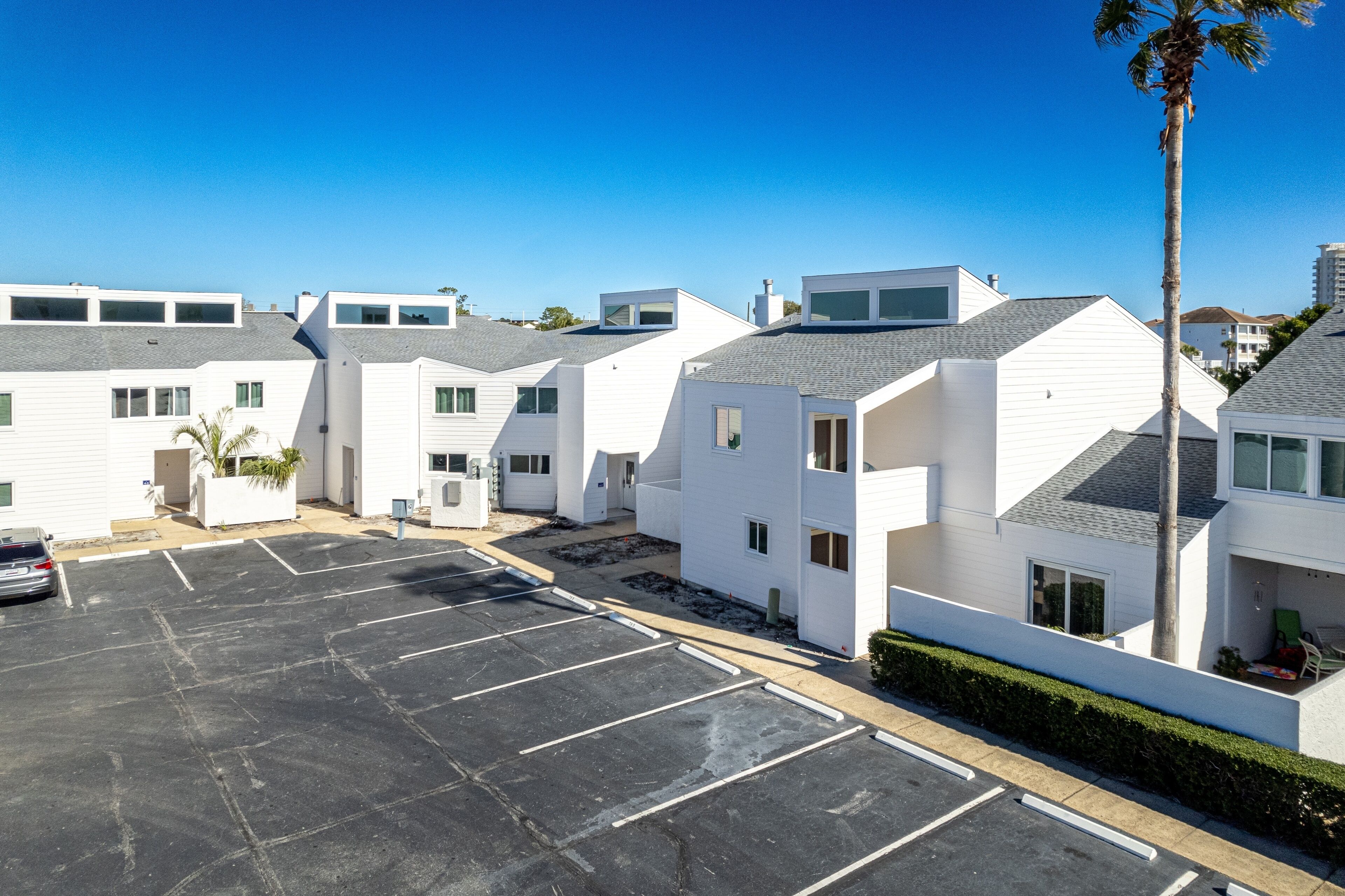 A row of modern white buildings with a parking lot in front.