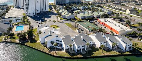 An aerial view of a coastal hotel complex with multiple buildings, a swimming pool, and a marina.