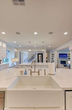 A modern kitchen with a large island, stainless steel appliances, and a view to the living area. - Villa de Lago! A Stunning Waterfront Estate on Lake Conroe (Montgomery)