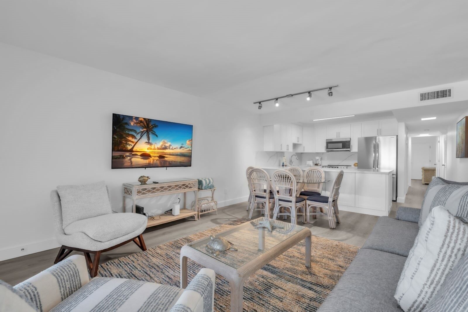 Een moderne woonkamer met een bank, fauteuils, een salontafel en een eethoek met stoelen en een tafel.