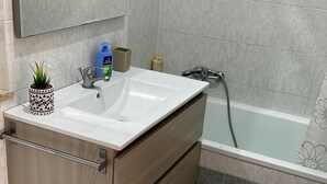 A bathroom with a white sink, wooden vanity, a mirror, a shower, and a toilet. - Bright & Peaceful 2BR Apartment in Terracina (Terracina)
