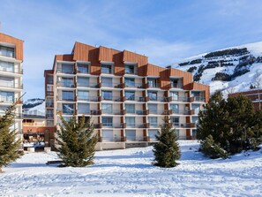 Ein mehrstöckiges Hotel mit modernem Design, mit Balkonen und Blick auf einen verschneiten Berg.