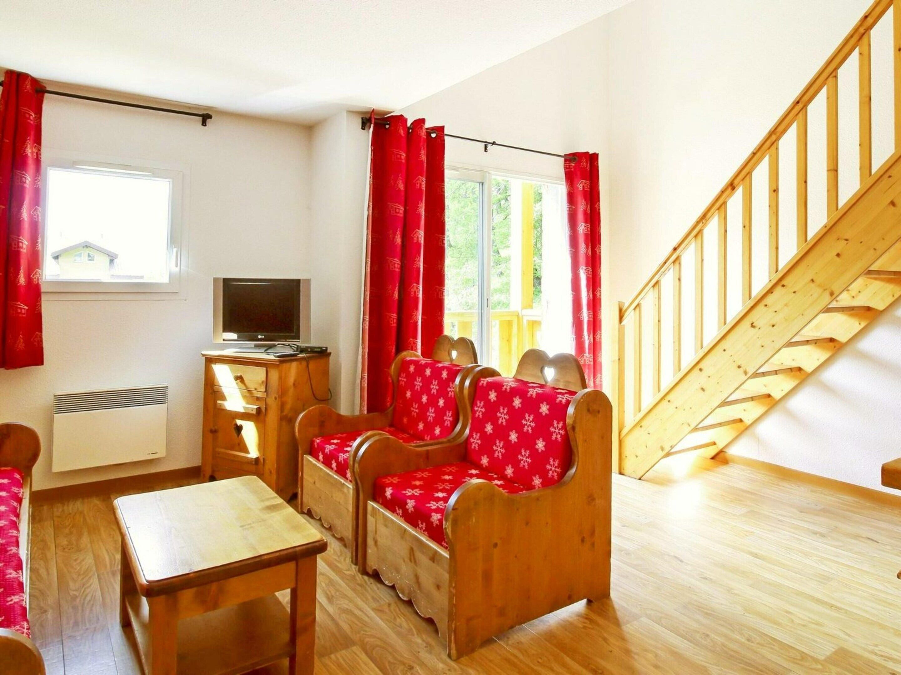 A room with a wooden staircase, a TV, a desk, and a sofa set.