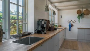 Een moderne keuken met een groot raam, roestvrijstalen apparatuur en een houten aanrecht.