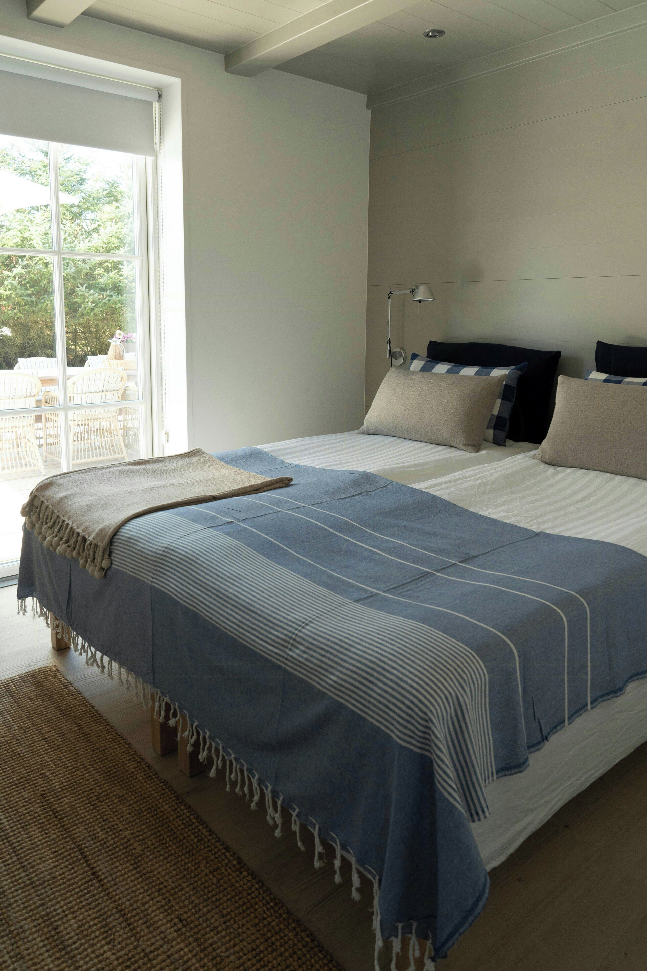 Een slaapkamer met een groot bed, een raam en uitzicht op buitenmeubilair.