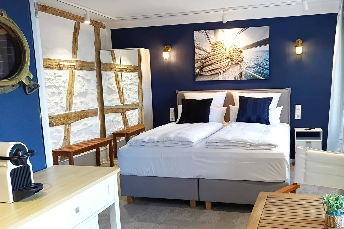 Siististi järjestetty hotellihuone, jossa on sänky, yöpöydät, työpöytä ja tuoli.