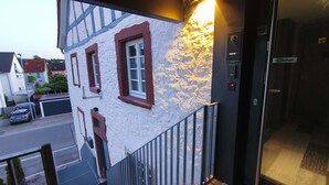 Un edificio con fachada blanca y marcos de ventana rojos, una escalera metálica y un ascensor.