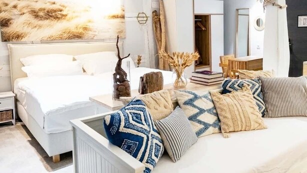 A modern bedroom with a large bed, bedside tables, and a variety of pillows. - NOX Hotel (Walzbachtal)