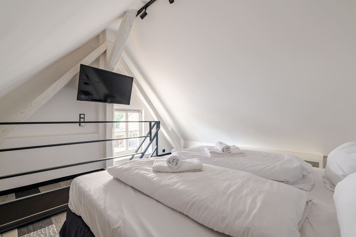 Un dormitorio con dos camas, un televisor montado en la pared y una ventana.
