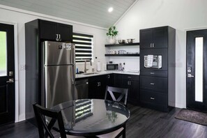 A modern kitchen with a stainless steel refrigerator, a microwave, and black cabinets. - Robyn's Nest -Sky Ridge Retreats - Views- Hot Tub (Denniston)