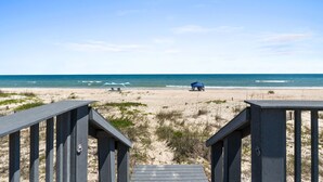 A beach with a wooden walkway leading to a blue umbrella. - Beachfront Breeze: Beachfront, Close to town center, Pet friendly, direct beach (St. George Island)