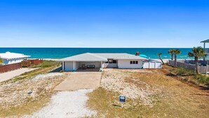 A beachfront property with a covered patio, a sandy driveway, and a view of the ocean. - Beachfront Breeze: Beachfront, Close to town center, Pet friendly, direct beach (St. George Island)