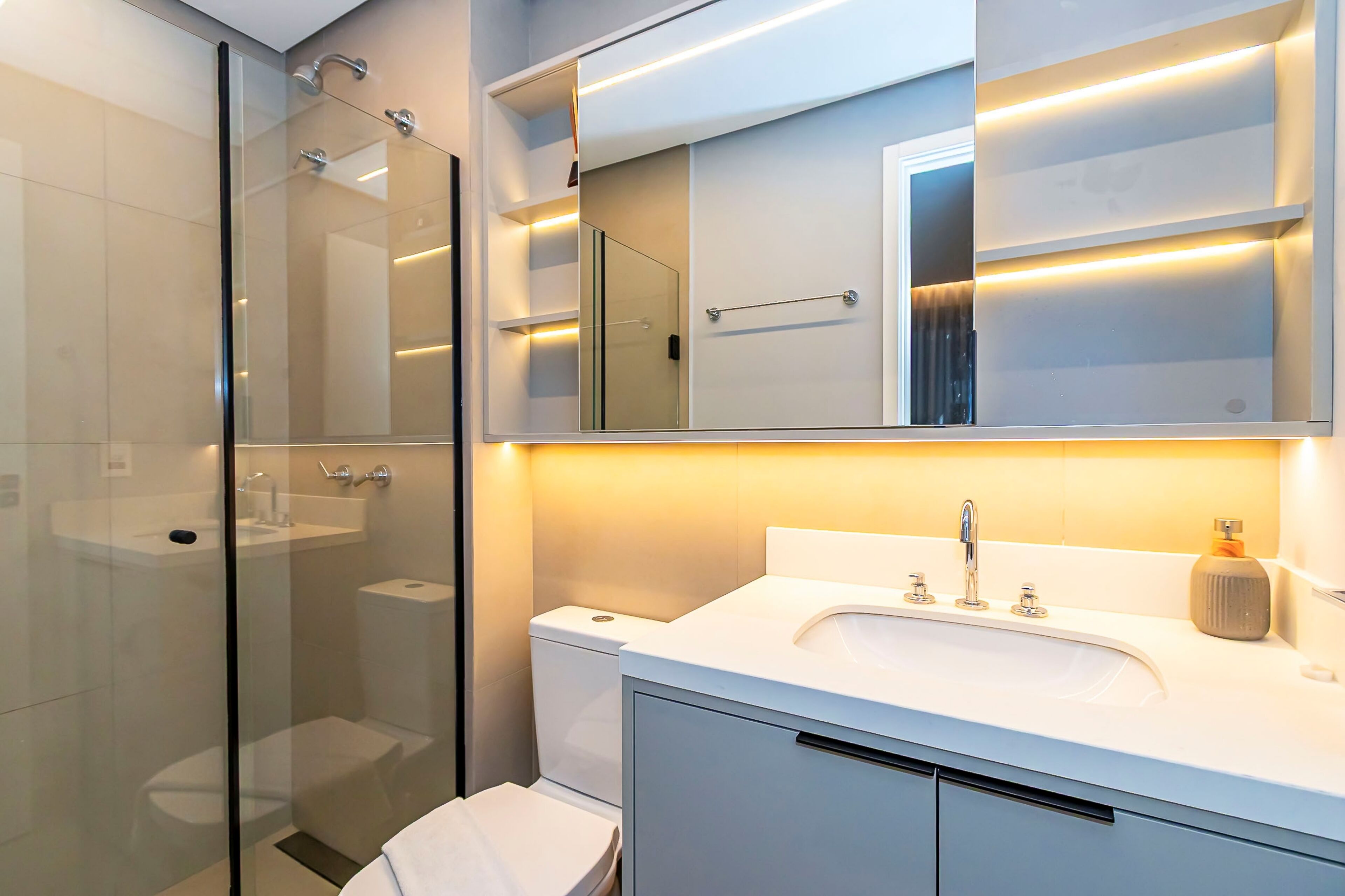 Een moderne badkamer met een douchecabine van glas, een wit wastafelmeubel en een spiegel erboven.