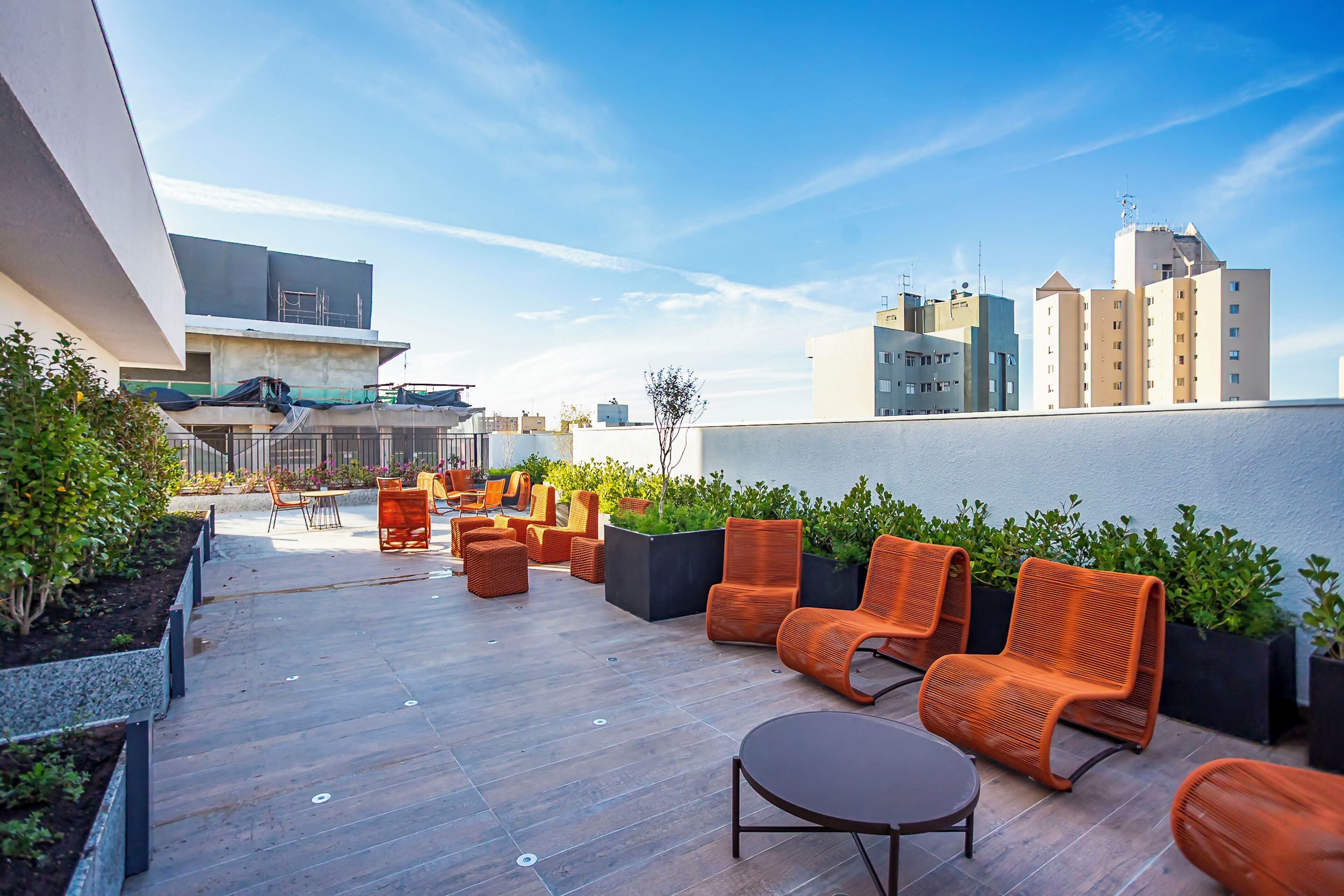 Una terraza en la azotea con mesas al aire libre, una pequeña mesa y plantas en macetas.