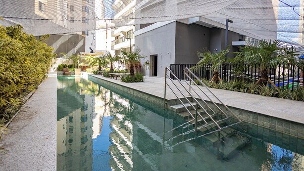 Una piscina interior con vistas despejadas a los edificios circundantes, un techo cubierto con mosquiteras y una escalera que sube a un nivel superior.