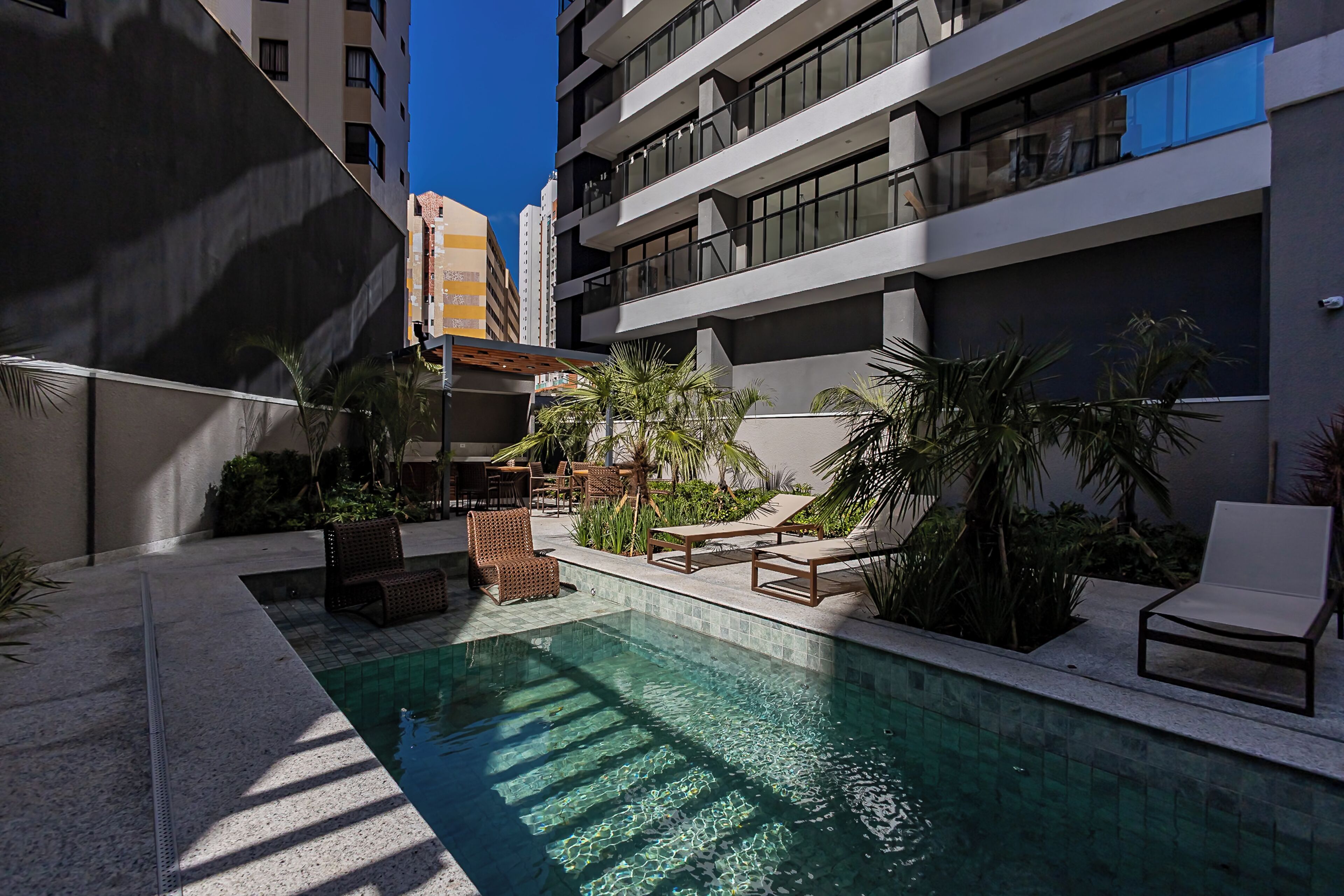 A pool area with lounge chairs, a small pool, and surrounding greenery.