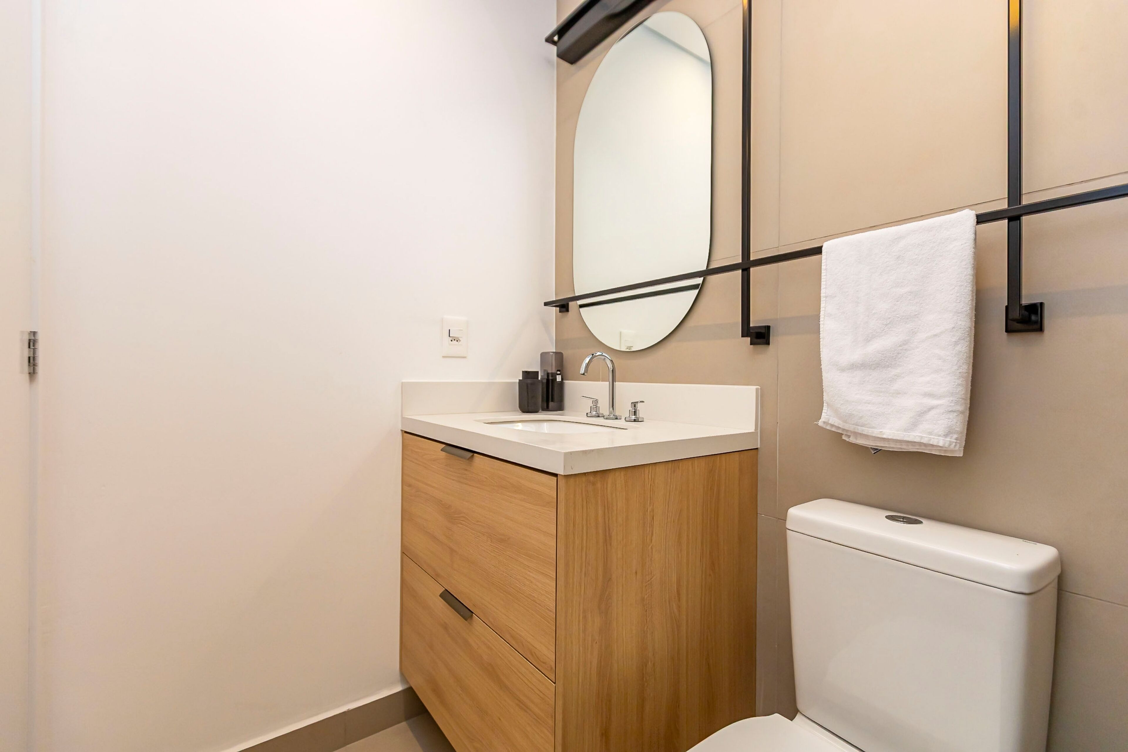 Une salle de bain avec un meuble-lavabo en bois, un lavabo blanc, un miroir et un porte-serviettes.