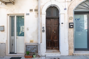 Facciata di un edificio con una porta in legno, una porta in vetro e un cartello con la scritta 'CAF'.