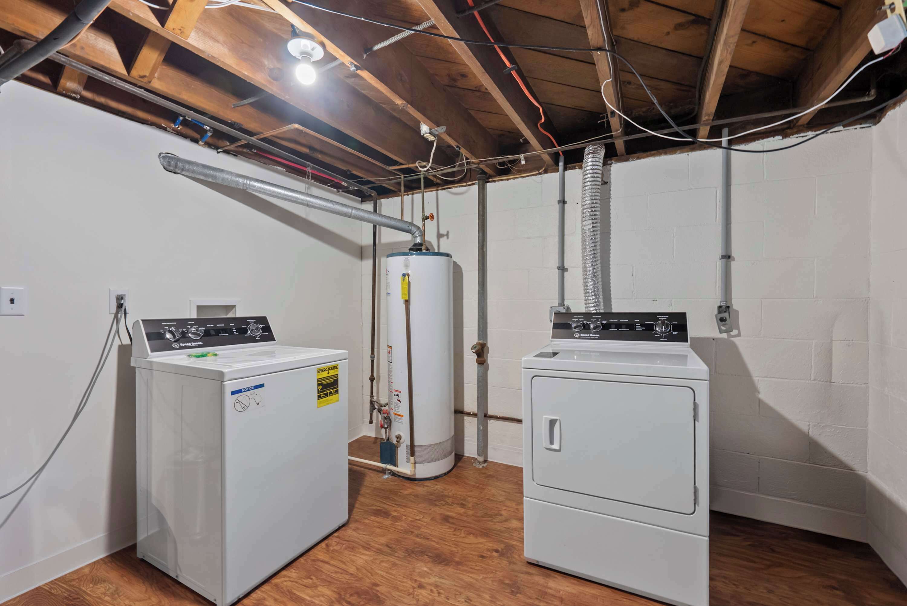 A laundry room with two front-loading washers, a water heater, and exposed ductwork.