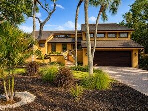 A modern two-story house with a garage, surrounded by landscaped gardens and palm trees. - Renovated 3/3.5 Pool home, Private Beach Access (Longboat Key)
