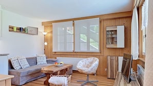 Een gezellige woonkamer met een bank, een fauteuil, een salontafel en een mand.