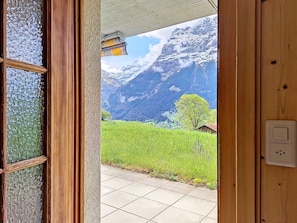 Eine Holztür, die zu einem Raum mit Blick auf eine Berglandschaft führt.