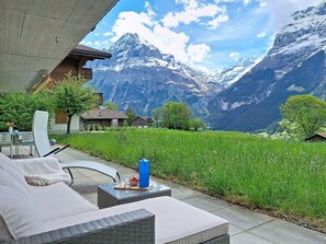 A patio with outdoor furniture, a view of snow-capped mountains, and a grassy area. - Lovely apartment for 2 people with WIFI, TV and terrace (Unter Eiger)