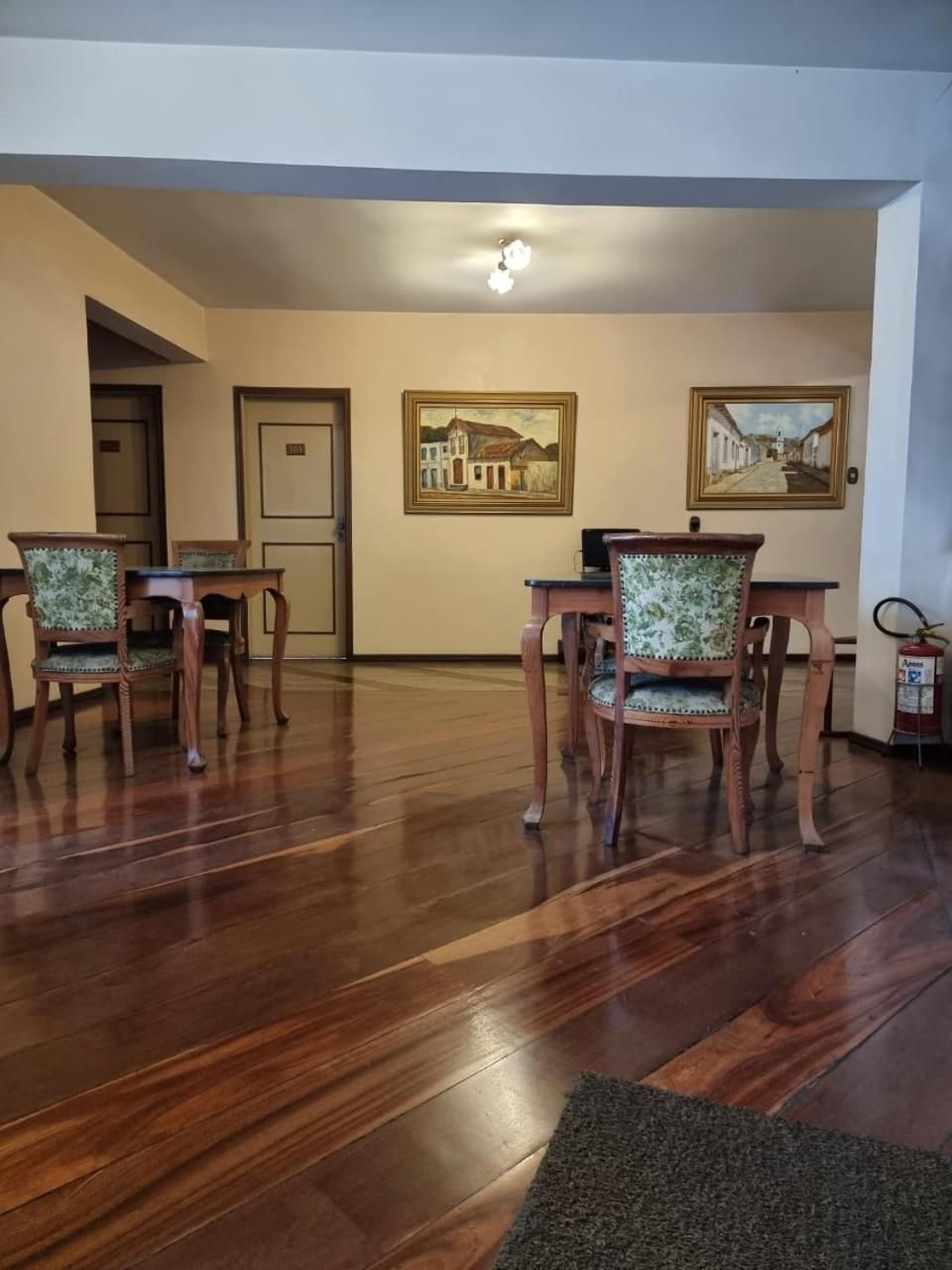 Uma área de refeições com piso de madeira, duas mesas e cadeiras.