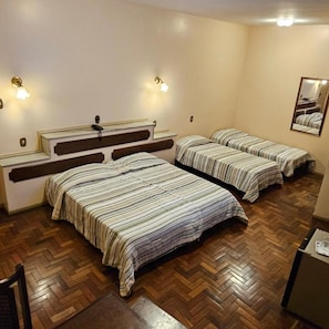Une chambre d’hôtel avec deux lits, un plancher en bois, des lampes de chevet et un miroir au mur.