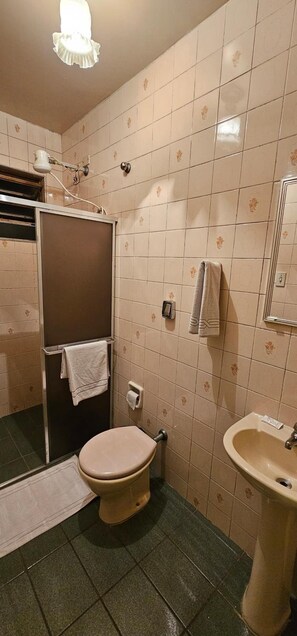 Une salle de bain comprenant des toilettes, un lavabo et un espace douche.