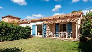 A house with a tiled roof, a covered patio with chairs, and a well-maintained lawn. - Home for 4 With Private Parking (Homps)