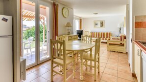 A dining area with a table and chairs, a sofa, a television, and a kitchen area with a refrigerator. - Home for 4 With Private Parking (Homps)