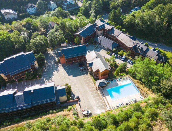 Eine Vogelperspektive auf ein Hotel mit mehreren Gebäuden, einem Schwimmbad und umgebender Bepflanzung.