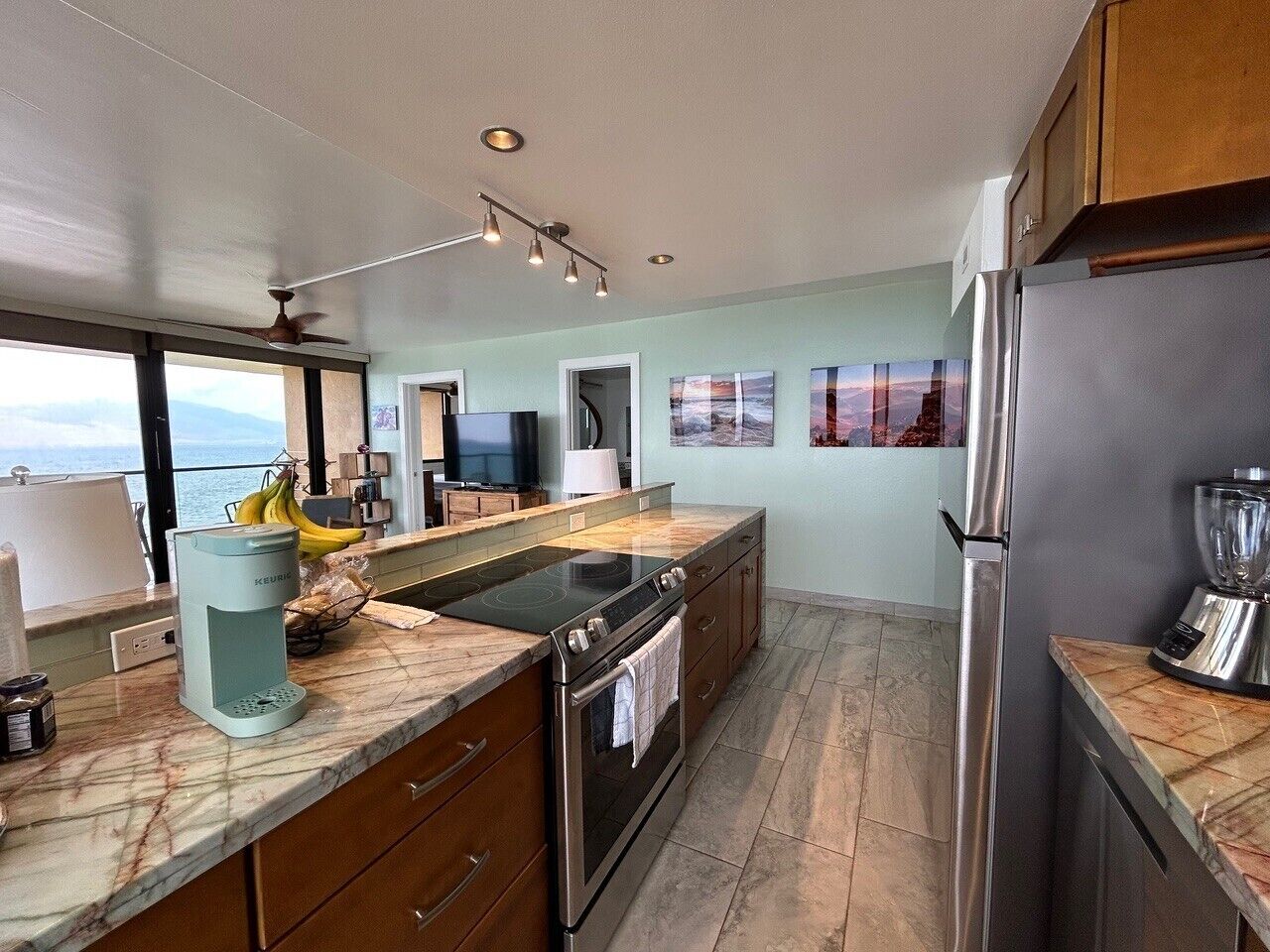 A modern kitchen with a large island, built-in appliances, and a view of the ocean.
