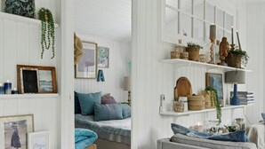 Ein Zimmer mit einem Bett, einem grauen Sofa und einem Regal mit Dekoration.