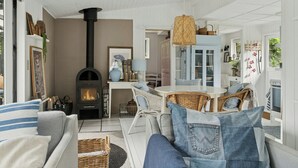 Ein gemütliches Wohnzimmer mit Kamin, Korbmöbeln und einem Essbereich.
