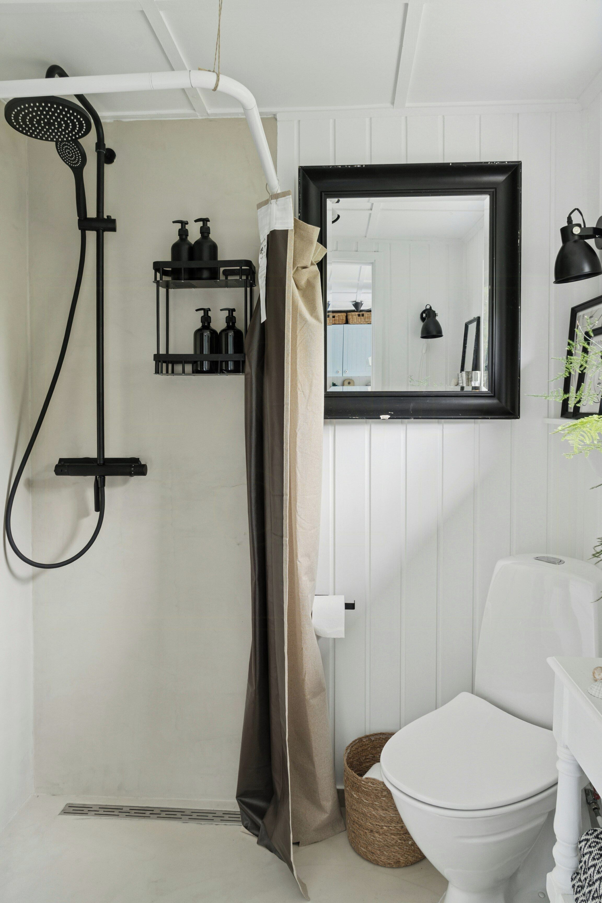 A bathroom with a shower, toilet, and a mirror.