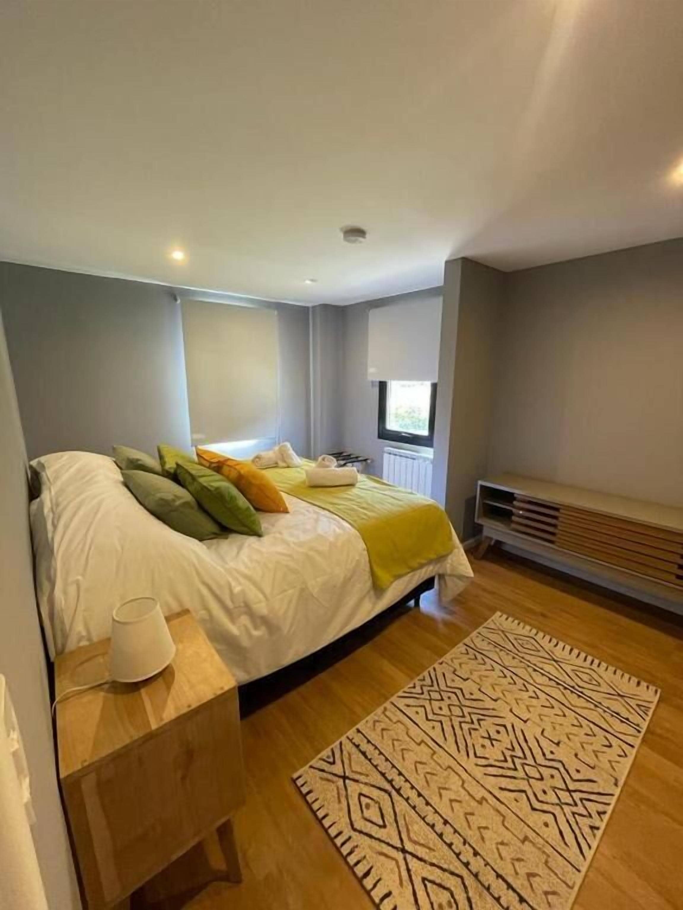 Une chambre à coucher moderne avec un lit, une table de chevet et un tapis à motifs.