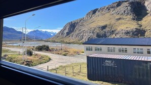 Un paysage montagneux avec un bâtiment portant l’inscription « INE C » et un conteneur maritime.