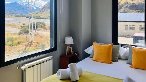 Une chambre d’hôtel avec un lit, une table de chevet, une lampe et une vue sur les montagnes.