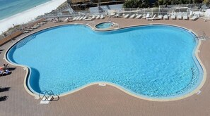 Ein großer, ovaler Pool mit einer Ziegelterrasse, in Strandnähe gelegen.