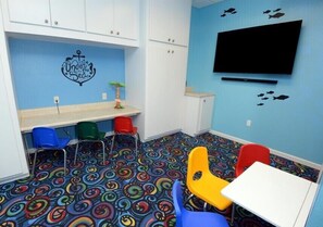 Ein Kinderspielzimmer mit bunnem Boden, einem weißen Tisch und Stühlen.