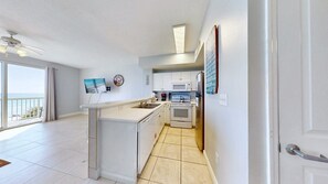 A modern kitchen with a central island, white cabinetry, and a view to the outside.