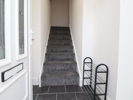 A staircase with carpeted steps leading to an upper floor, a door with a glass panel, and a metal handrail on the right.