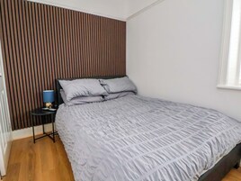 A bedroom with a bed, a nightstand, a lamp, and a window.