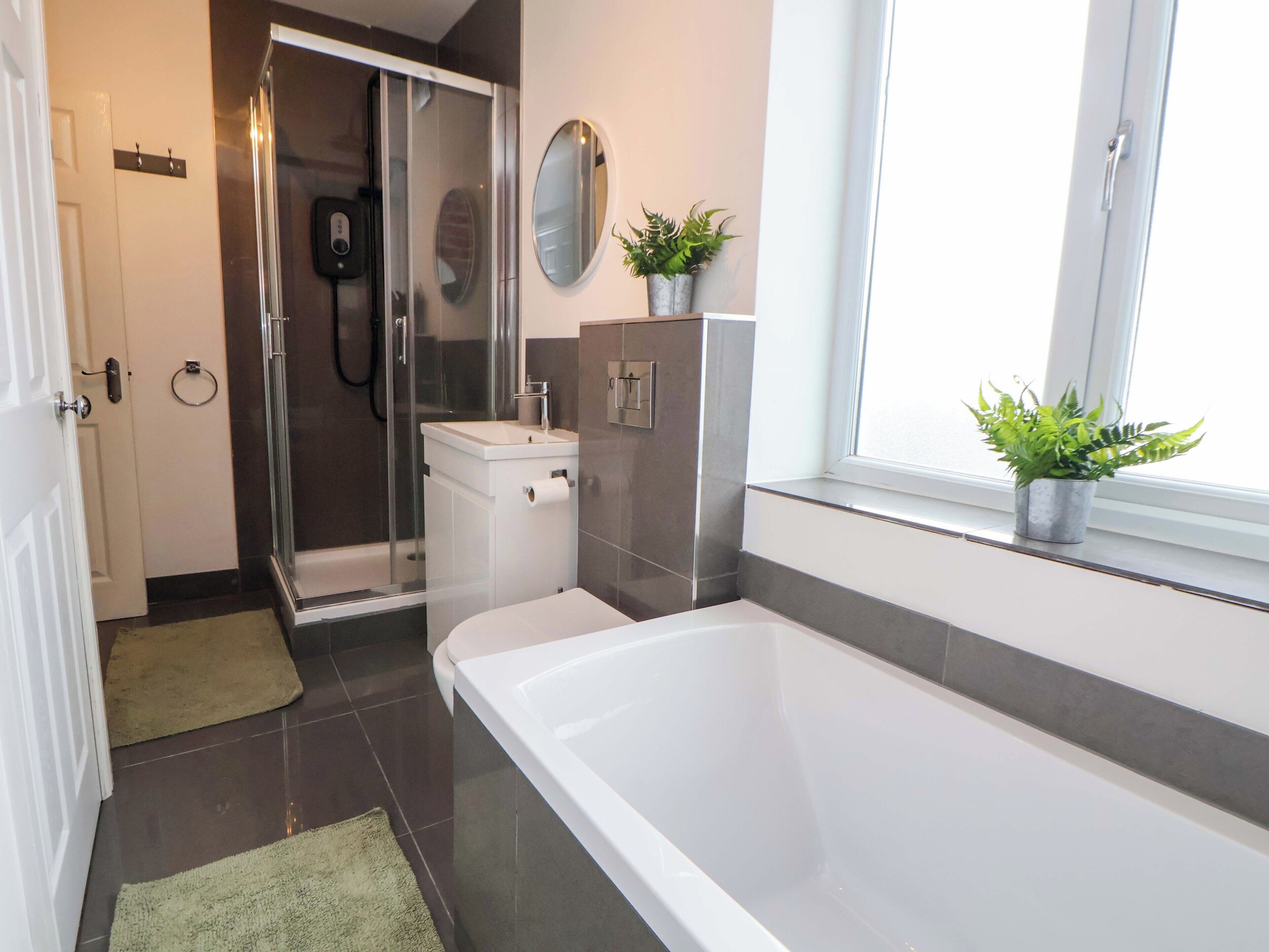 A modern bathroom with a bathtub, a shower, a toilet, and a sink.