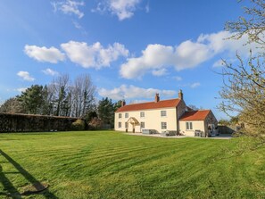 Une grande maison avec un toit rouge, une pelouse bien entretenue et un ciel bleu dégagé.