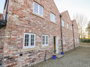 A brick building with multiple windows, a door, and a gravel driveway. - Tuft House (York)